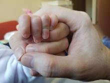 A photo of Walid, his wife, and his daughter holding hands. 